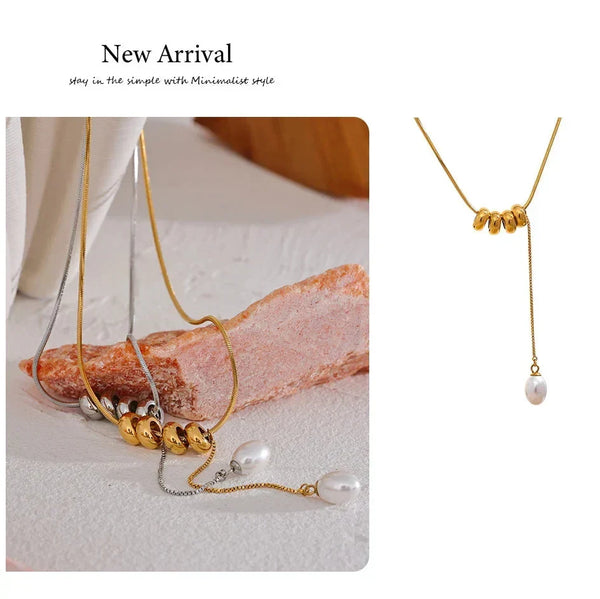 Gold necklace with pearl pendants on a textured surface