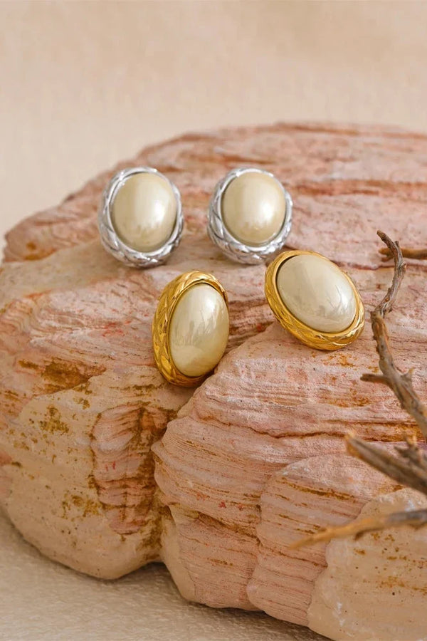 Pair of pearl earrings on a textured stone surface