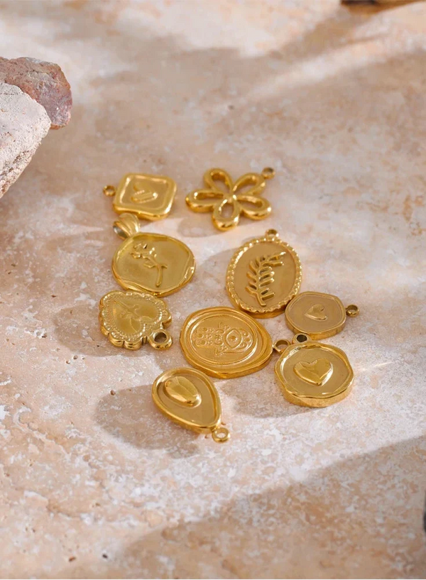 Gold jewelry charms on a textured stone surface