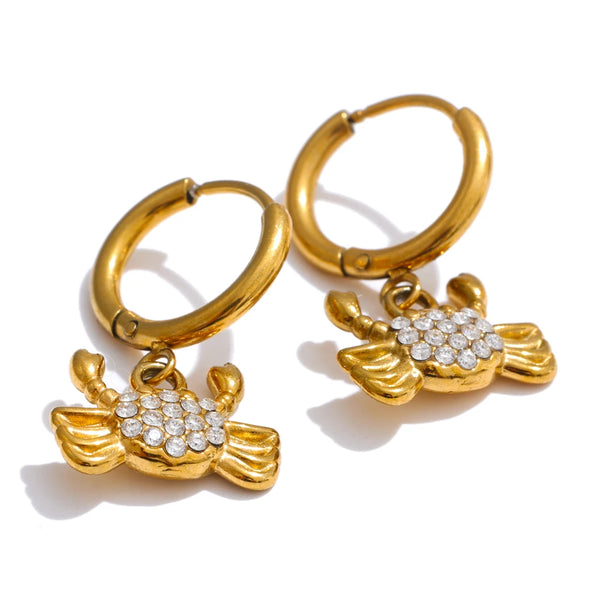 A pair of gold hoop earrings with dangling lobster claw charms embellished with small clear crystals, shown on a white background.