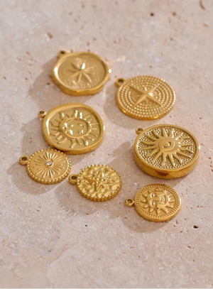 Set of gold circular pendants with intricate designs on a beige surface