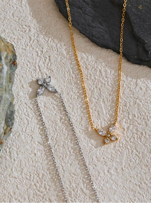 Two necklaces, one gold and one silver, on a textured stone surface.