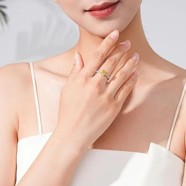 Woman wearing Amber Luxe Engagement Ring - TM & CO. JEWELS - Ring with a yellow gemstone and diamond accents on a white background.