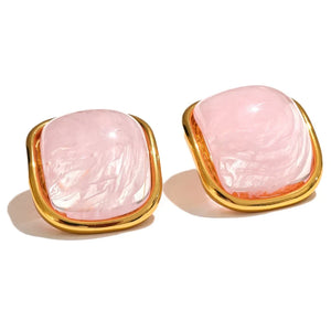 Pair of pink earrings with gold frames on a white background