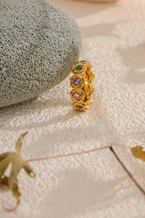 Gold ring with colorful gemstones on a textured surface