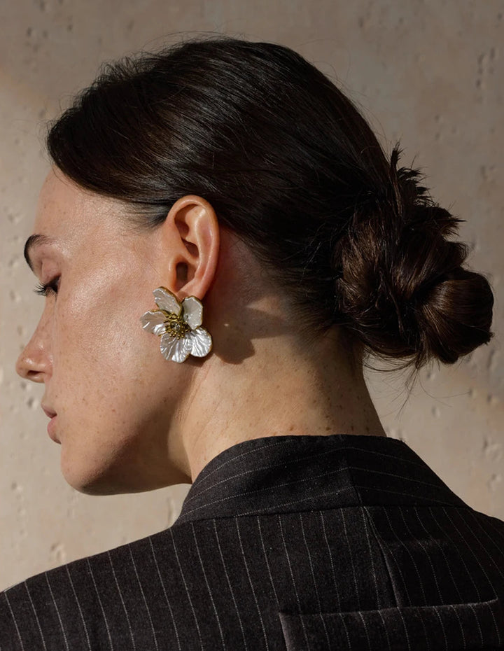 Woman wearing a floral earring with a neutral background