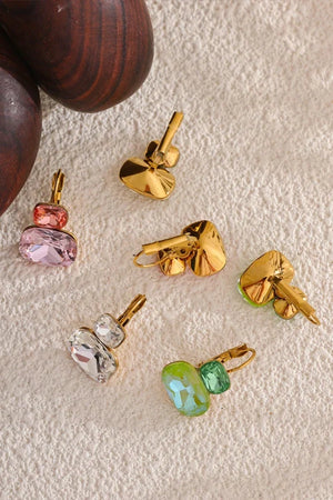 Gold and gemstone pendants on a textured beige surface