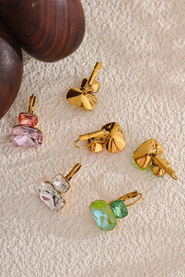 Gold and gemstone pendants on a textured beige surface