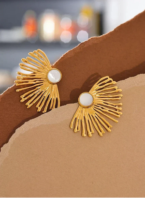 Gold earrings with white centers on a brown surface