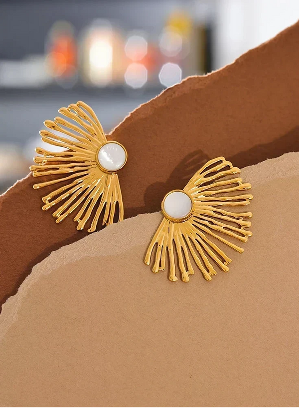 Gold earrings with white centers on a brown surface