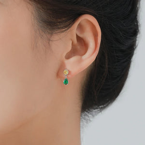 Close-up of an ear wearing a pair of earrings with colored gemstones.