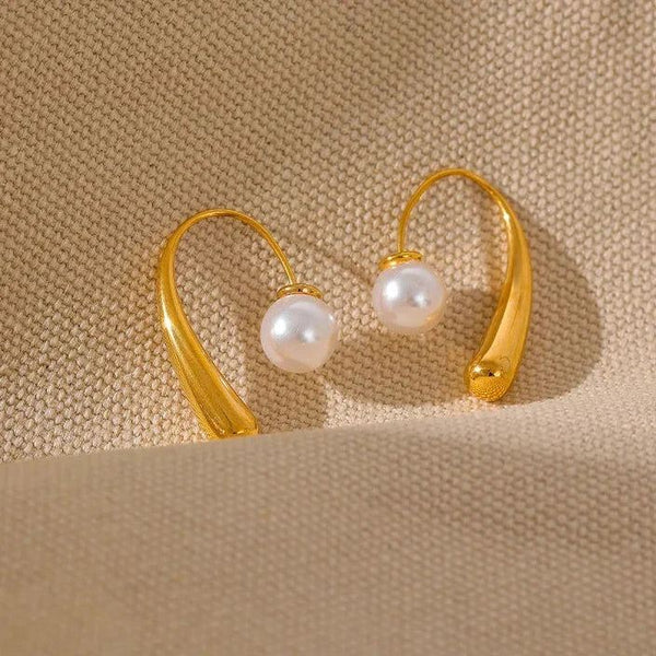 Gold hoop earrings with pearls on a beige background