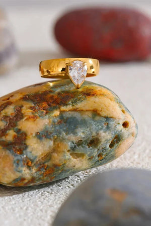 Gold ring with a heart-shaped gemstone on a textured stone surface