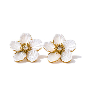 Pair of white floral earrings with gold accents on a white background