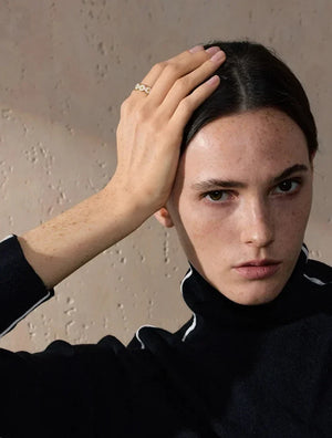 Woman with hand on head against a neutral background
