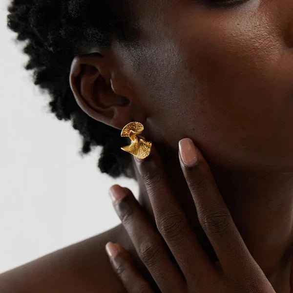 Gold earring worn by a person with a neutral background