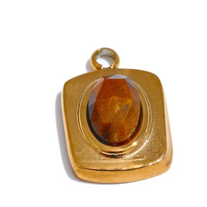 Gold pendant with a brown stone on a white background