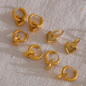 Gold jewelry pieces including rings and pendants on a textured beige -Close-up of a woman Astral Affection Hoops - TM & CO. JEWELS 
