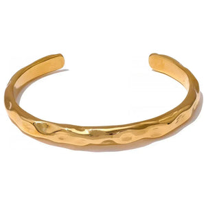 18K gold-plated hammered cuff bracelet on textured fabric background