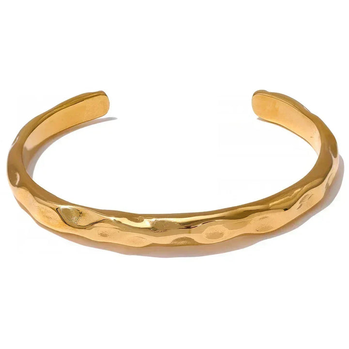 18K gold-plated hammered cuff bracelet on textured fabric background