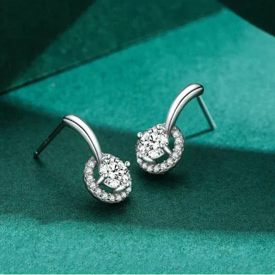 Silver earrings with clear gemstones on a green fabric background