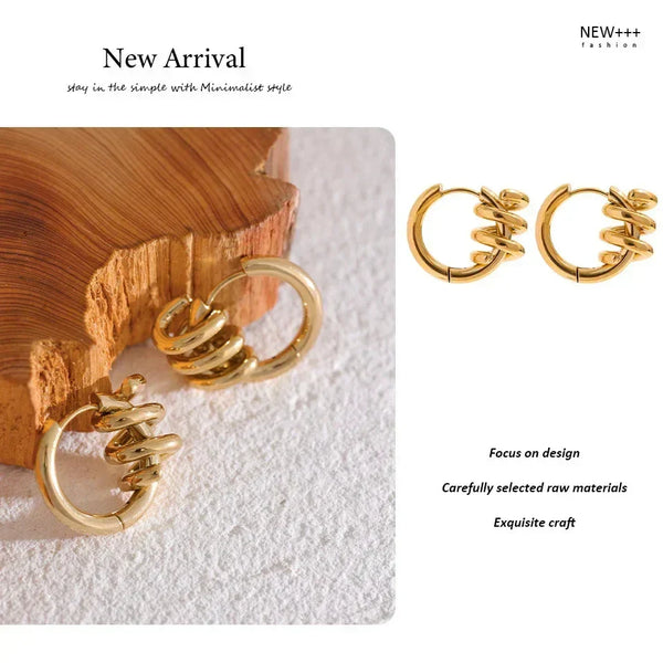 Gold spiral earrings on a textured surface with 'NEW++' branding.