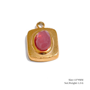 Gold pendant with a red stone on a white background