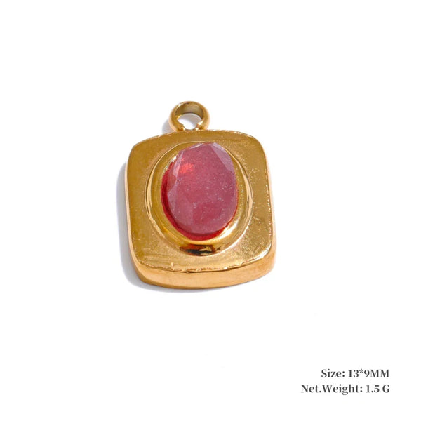 Gold pendant with a red stone on a white background
