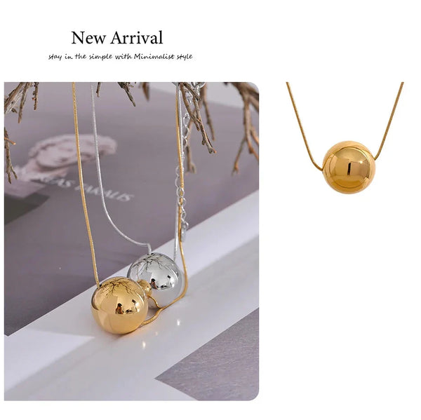 Gold and silver necklace with spherical pendants on a white surface.