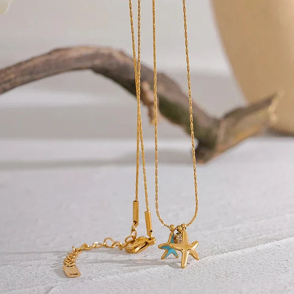Two gold necklaces with starfish pendants on a light surface.