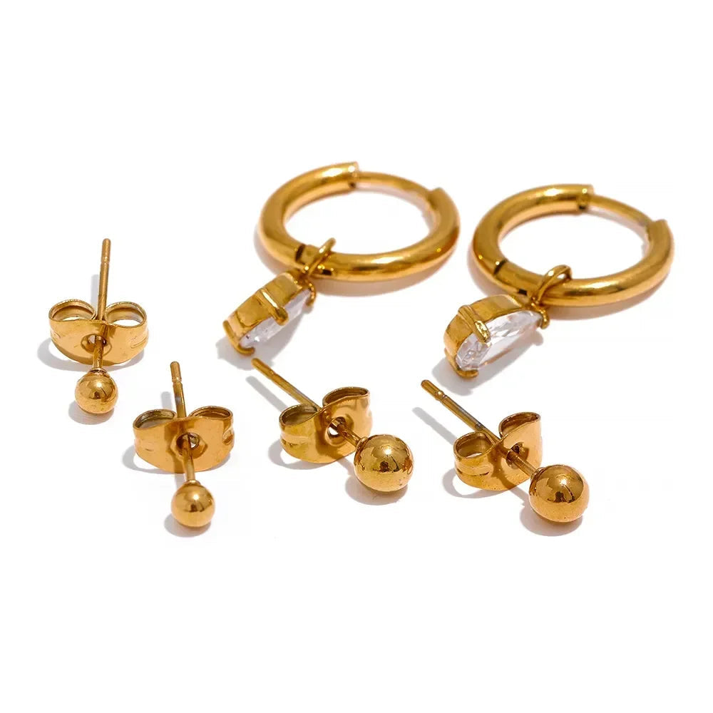Set of gold hoop and ball earrings on a white background.