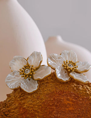 Floral earrings with gold accents on a textured surface
