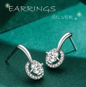 Silver earrings with gemstones on a teal background