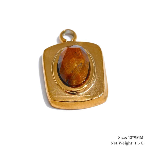 Gold pendant with a central amber-colored stone on a white background