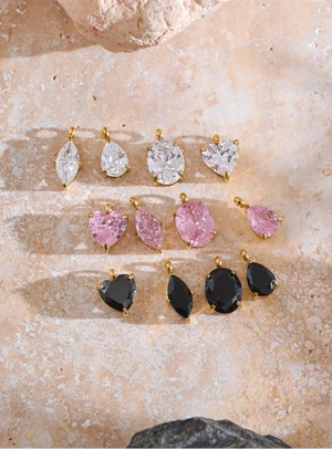 Set of earrings with various gemstones on a textured stone surface