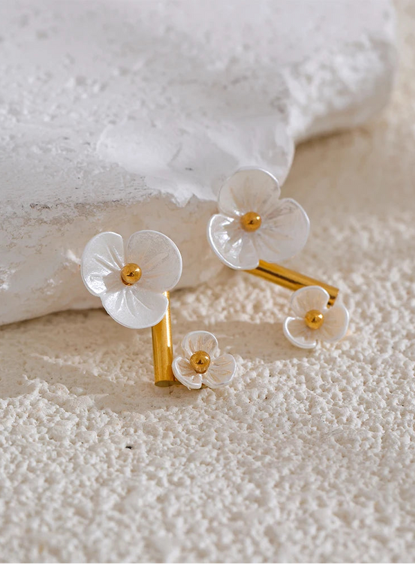 Floral earrings with gold accents on a textured white surface