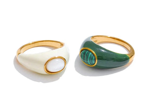 Two rings, one white and gold, the other green and gold, on a white background.