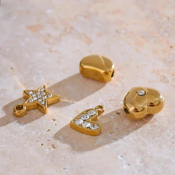 Gold charms with gemstones on a textured stone surface