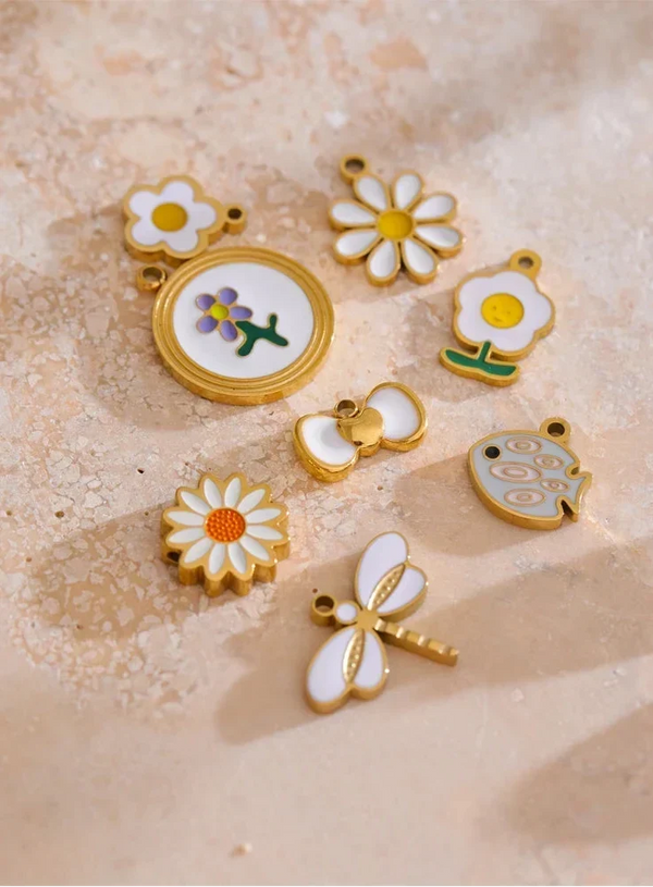 Set of floral and insect-themed charms on a textured beige surface