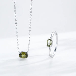 Silver necklace and ring with green gemstones on a white background