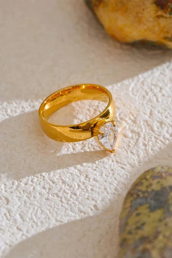 Gold ring with a diamond on a textured beige surface