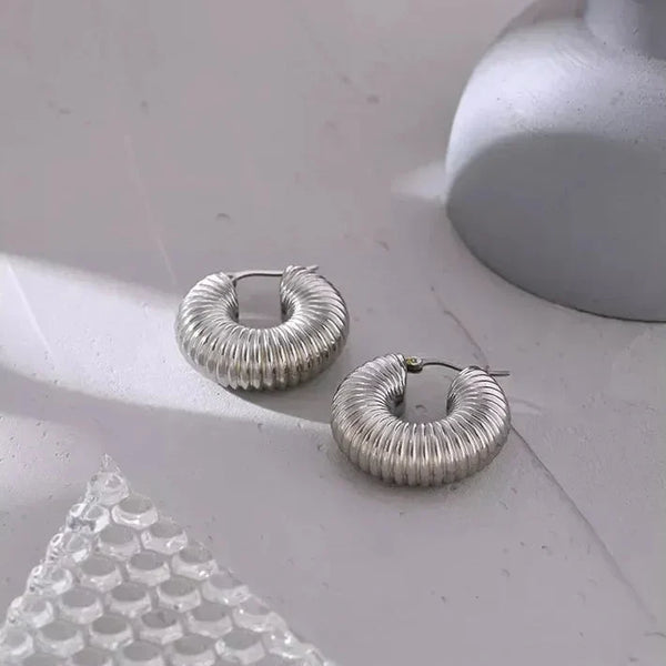 Textured 925 silver hoop earrings on a light surface, modern minimalist jewelry