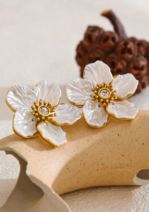 Floral earrings with gold accents on a textured surface