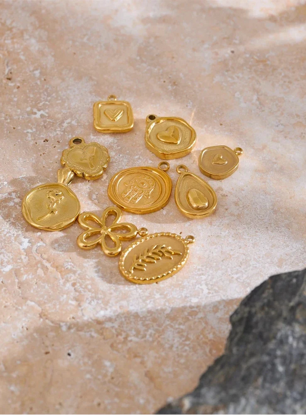 Gold jewelry charms on a textured stone surface