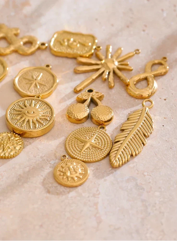 Collection of gold jewelry charms on a textured surface