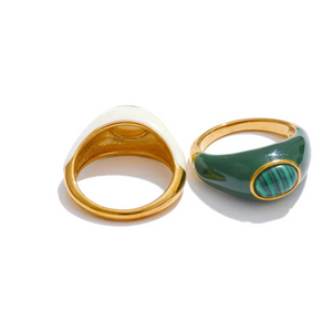 Two rings, one gold and white, the other green and gold, on a white background.