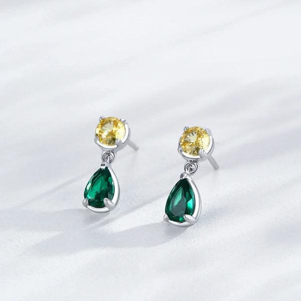 Pair of earrings with green and yellow gemstones on a light gray background