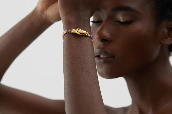 Woman wearing a gold bracelet on a neutral background