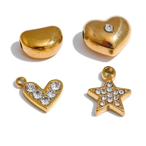 Gold heart and star-shaped pendants with embedded crystals on a white background.