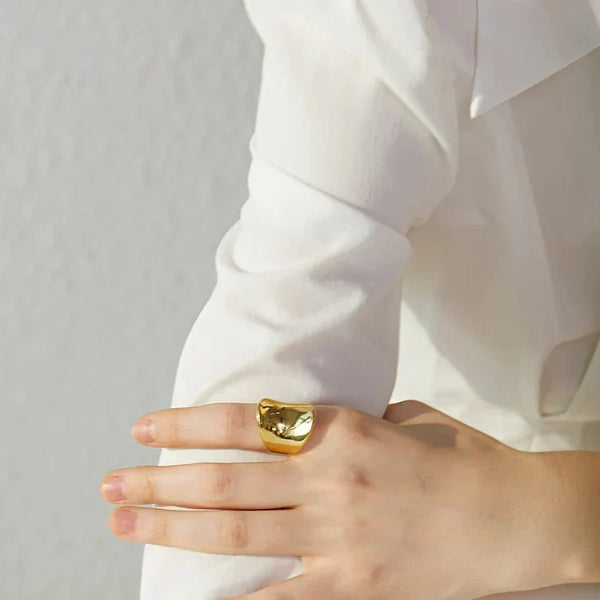 Woman wearing chunky gold-plated statement ring on hand, elegant jewelry close-up